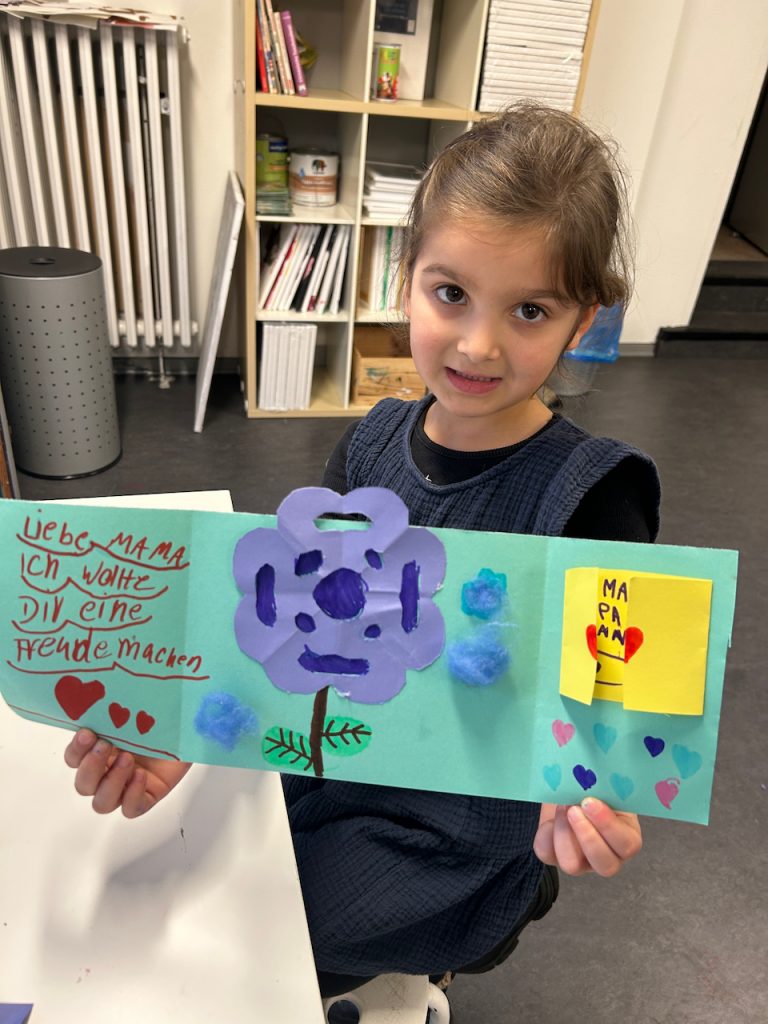 Stolz präsentiert ein Mädchen das im Kinderatelier Düsseldorf erschaffene Kunstwerk.